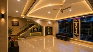 A hotel lobby with a reception desk, a staircase, a seating area, and a ceiling fan. - HOTEL RONIT ROYAL - DELHI AIRPORT  (New Delhi)