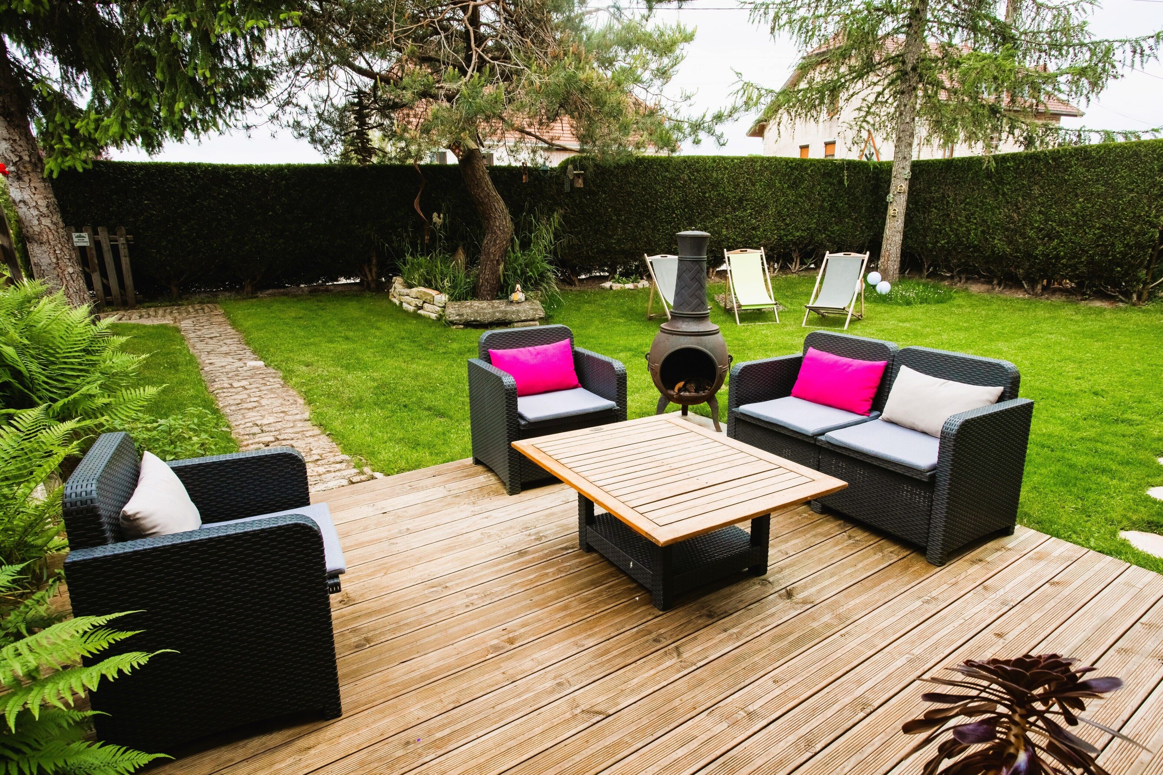 Une terrasse aménagée avec du mobilier d’extérieur, une table centrale et un élément décoratif en forme de foyer.