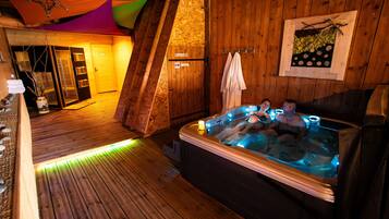 A wooden spa room with a hot tub, wooden flooring, and a wooden wall.