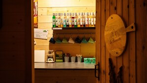 A bar area with stools, a counter with bottles, and a wooden wall with a sign.