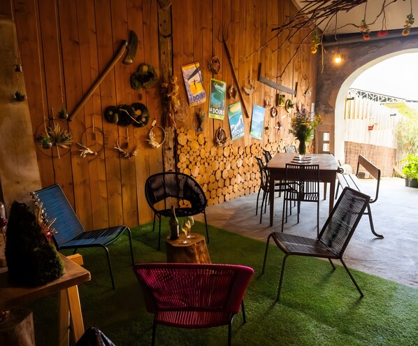 A rustic interior with wooden walls, a dining area, and outdoor seating.