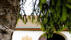 Un edificio rústico con tejado de tejas, cerca de madera y macetas colgantes.