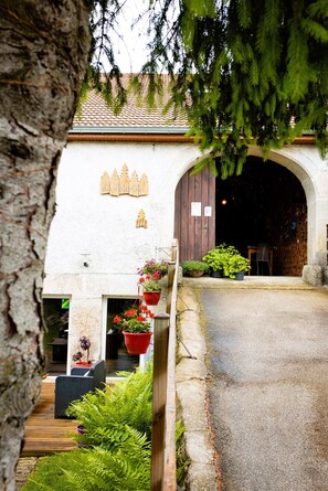 A rustic building with a tiled roof, wooden fence, and hanging flower pots.