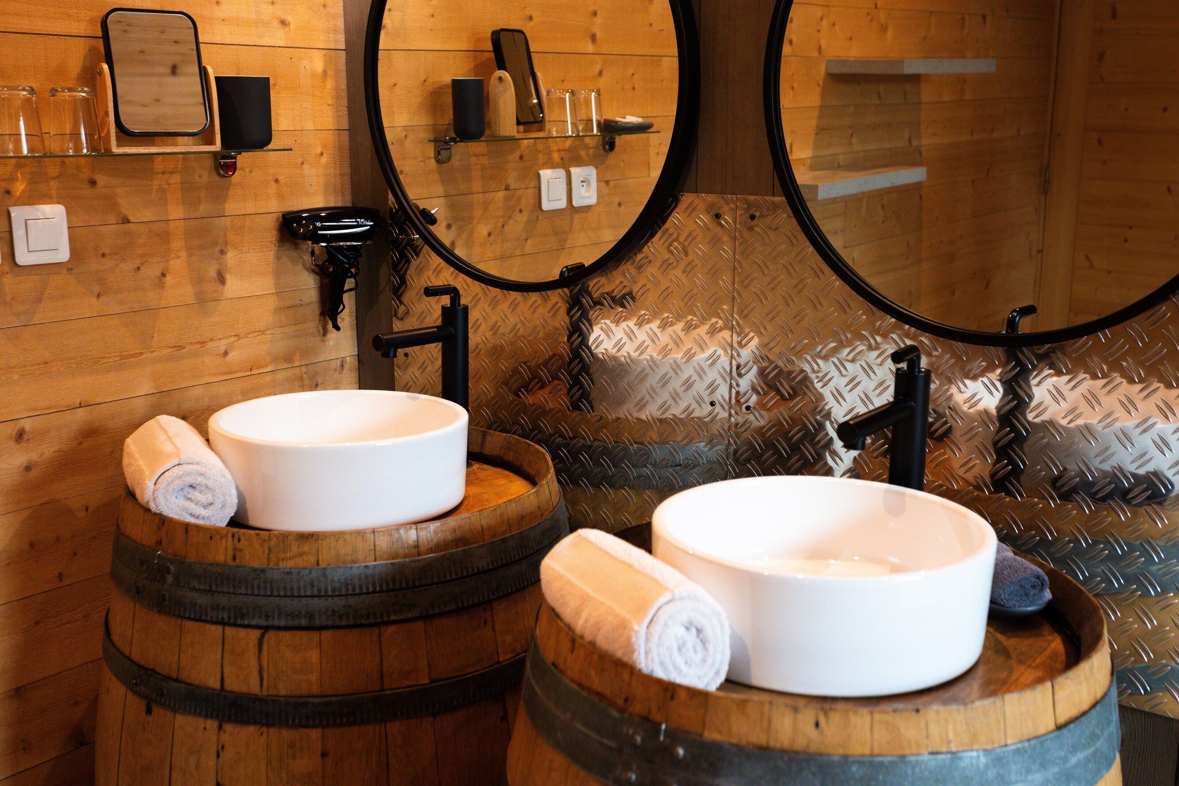 Ein Badezimmer mit Waschbecken aus Holzfässern, einem Spiegel und einem Handtuchspender.