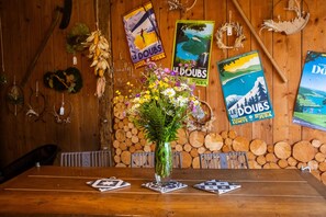 A wooden table with a vase of flowers, surrounded by posters on a wooden wall.