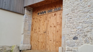 A wooden door with a sign reading 'CABANE CHEZ JULES' above it, set against a stone wall. - Guest Room “La Cabane et Spa Chez Jules” with Private Space and Wi-Fi (Vellerot-lès-Vercel)