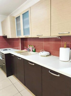 A kitchen with a white countertop, dark cabinets, and a red-tiled backsplash. - Valantis' urban nest (Chios)
