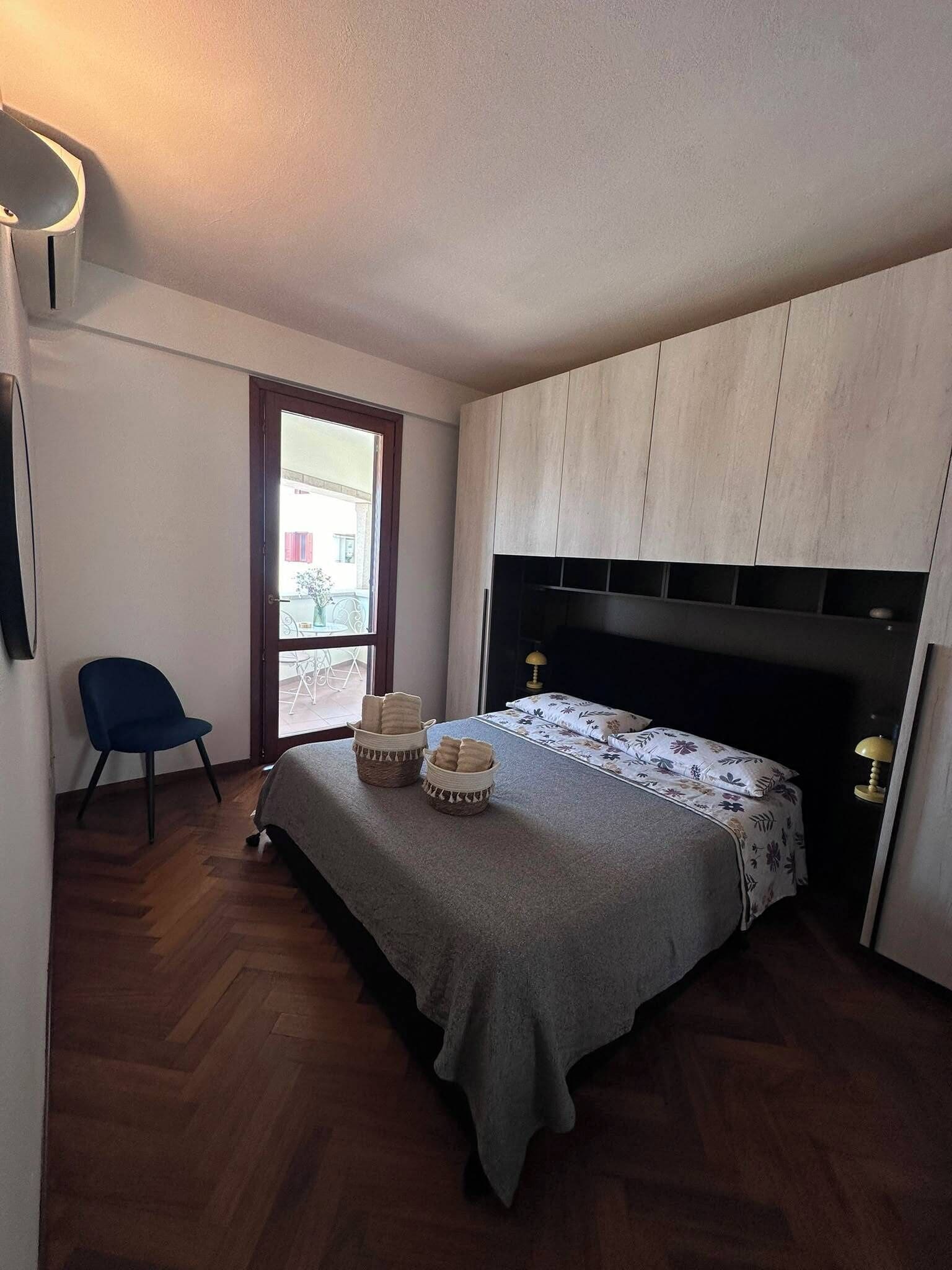 Una camera da letto con un letto, una sedia, una finestra e una porta.
