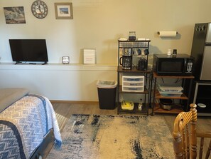 A hotel room with a bed, a TV, a coffee maker, a microwave, and a small kitchenette.