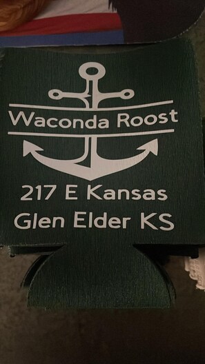 Señal con el texto 'Waconda Roost 217 E Kansas Glen Elder KS' sobre un fondo oscuro.