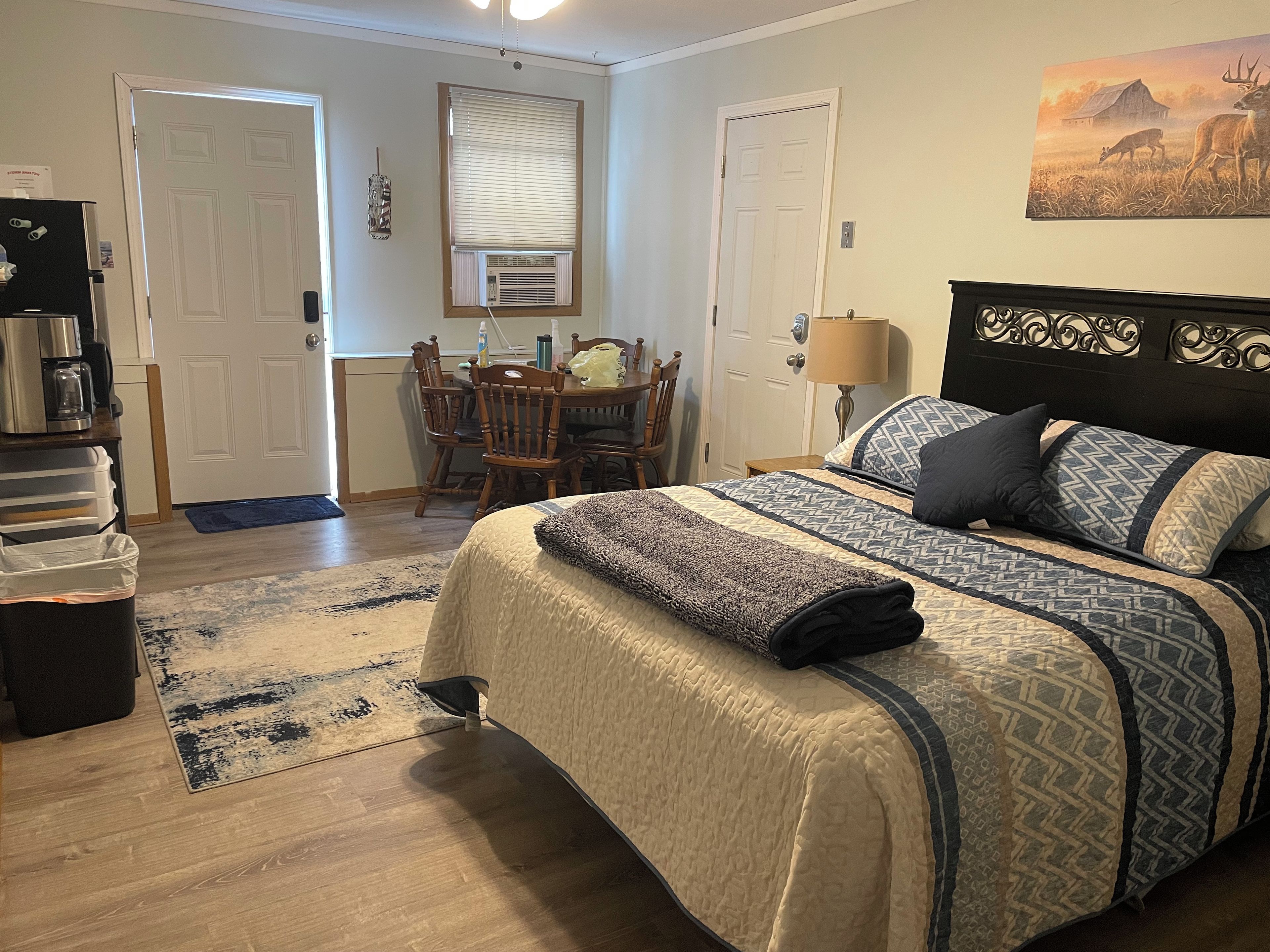 A bedroom with a bed, bedside table, lamp, and a painting on the wall.