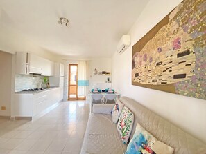 Ein modernes Interieur mit Küche, Essbereich und Wohnbereich, inklusive Sofa und großem Gemälde.
