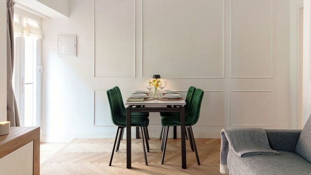 A dining area with a table set for four, two green chairs, a white tablecloth, and a vase with yellow flowers. - Incanto 107 - My Home in Como (Como)