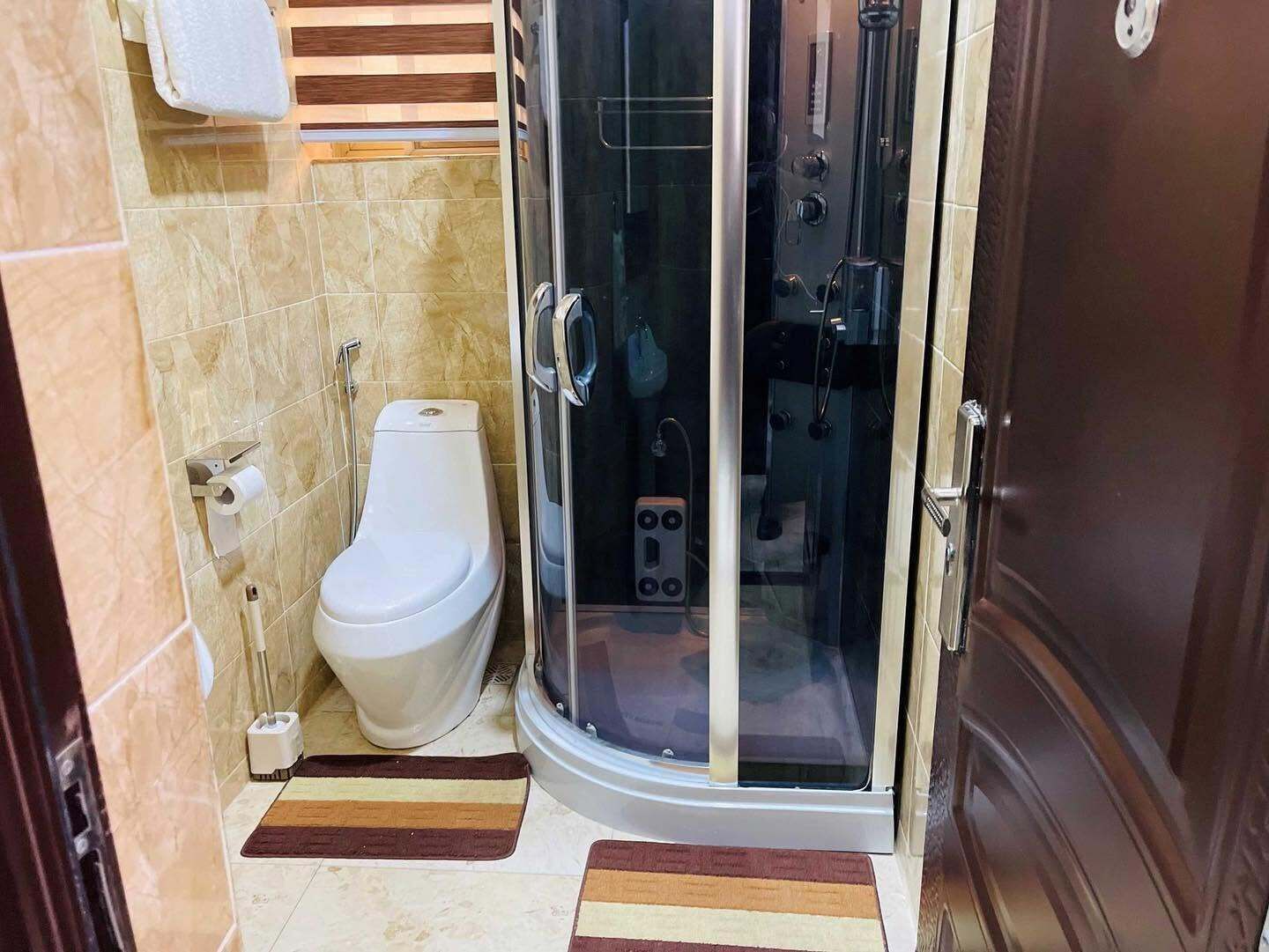 Un baño con inodoro, cabina de ducha y un perchero para toallas.