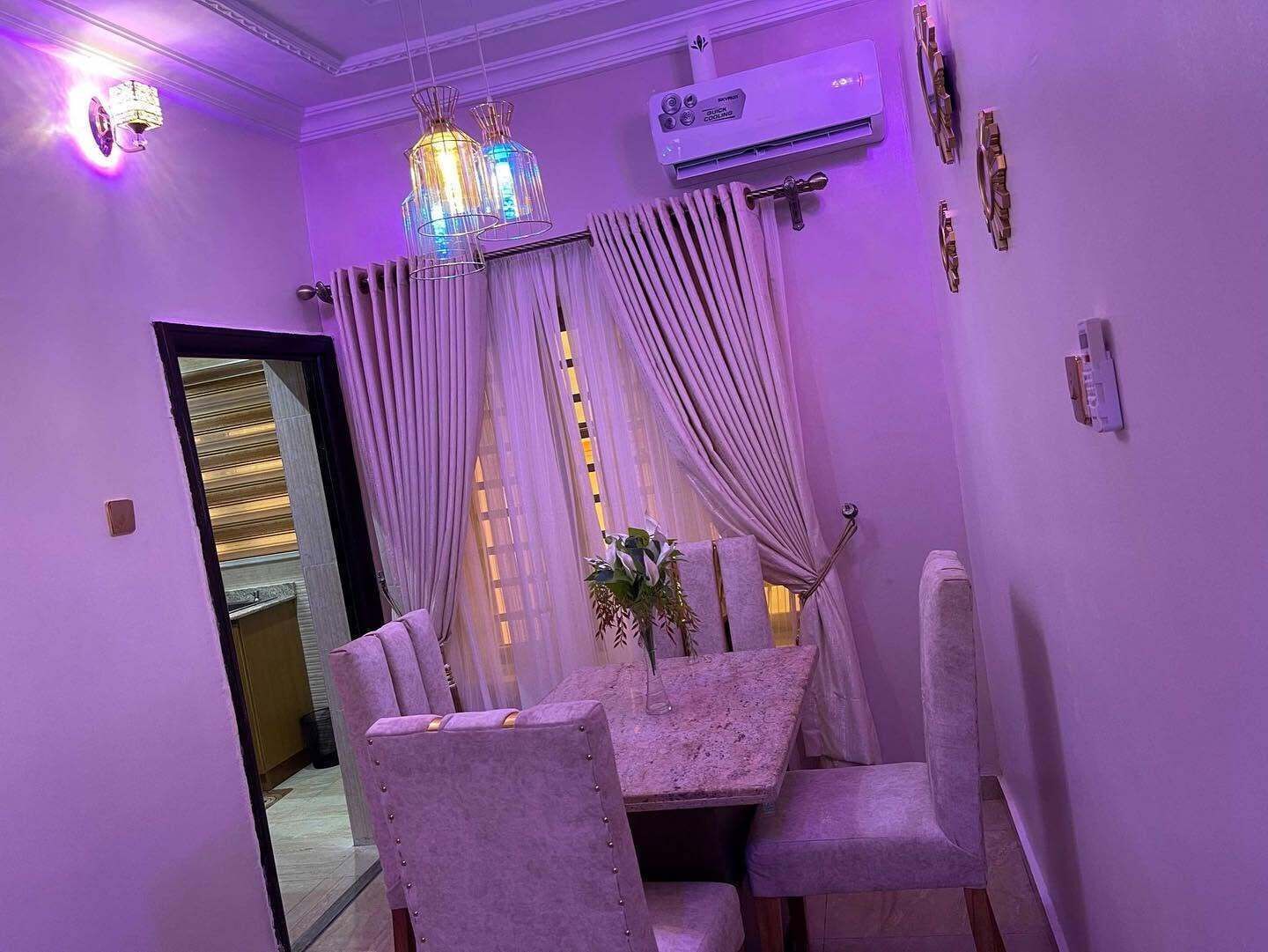 A dining area with a table and chairs, an air conditioning unit, and a chandelier.