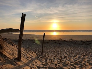 Ein Strand mit Holzzaun, Sonnenuntergang und ruhiger See.