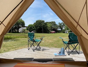 A tent with two chairs and a table set up on a wooden deck.