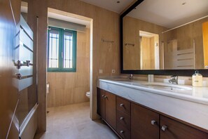 Un baño con un espejo grande, un lavamanos y un inodoro.