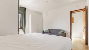 A bedroom with a large bed, a sofa, a door, and a window with curtains. - Villa Natura by BarbarHouse (Santa Cesarea Terme)
