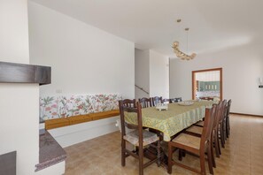 A dining area with a table set for six, surrounded by wooden chairs with cushioned seats. - Villa Natura by BarbarHouse (Santa Cesarea Terme)
