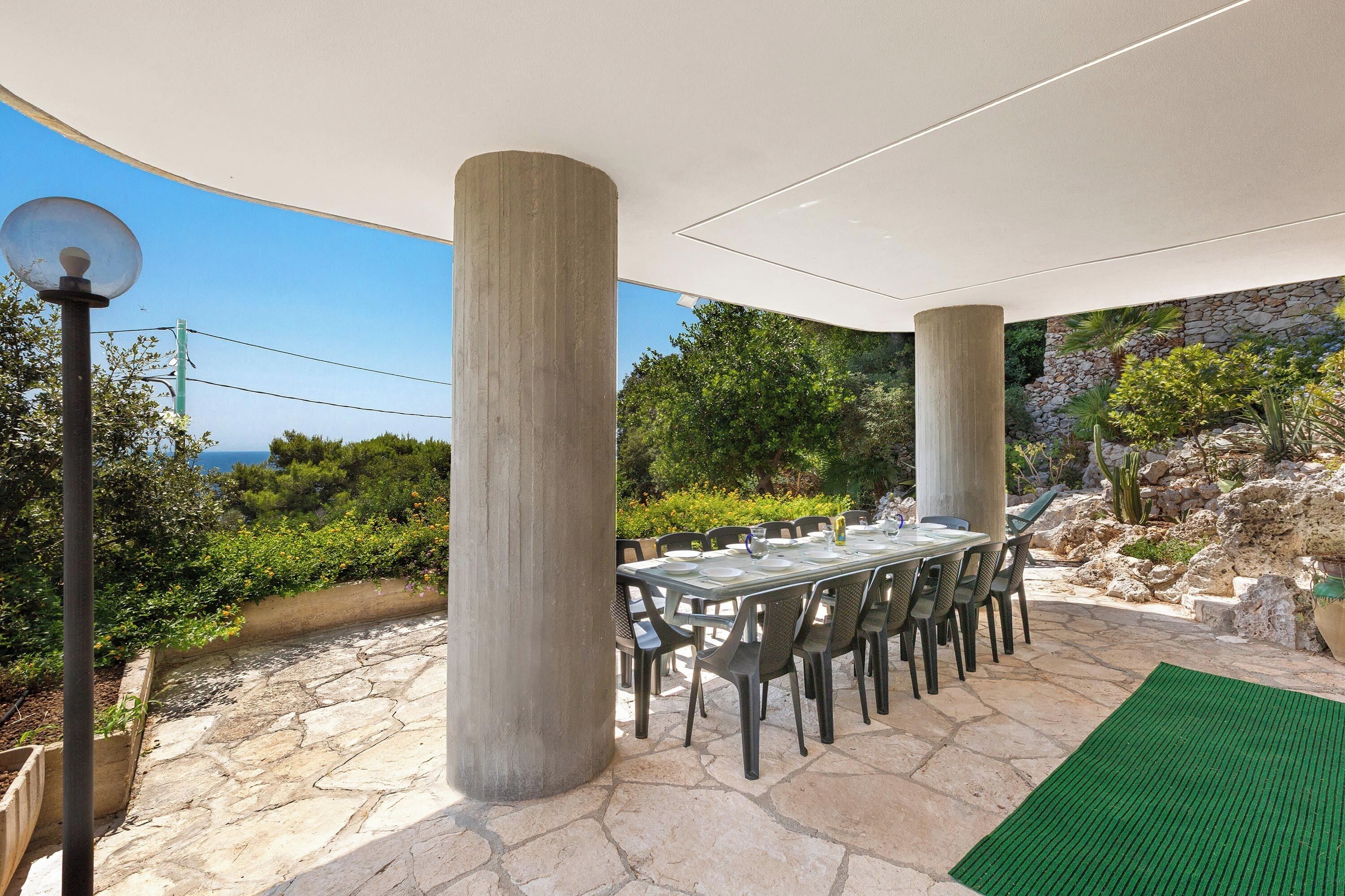 An outdoor dining area with a table set for six, surrounded by chairs, under a white canopy.