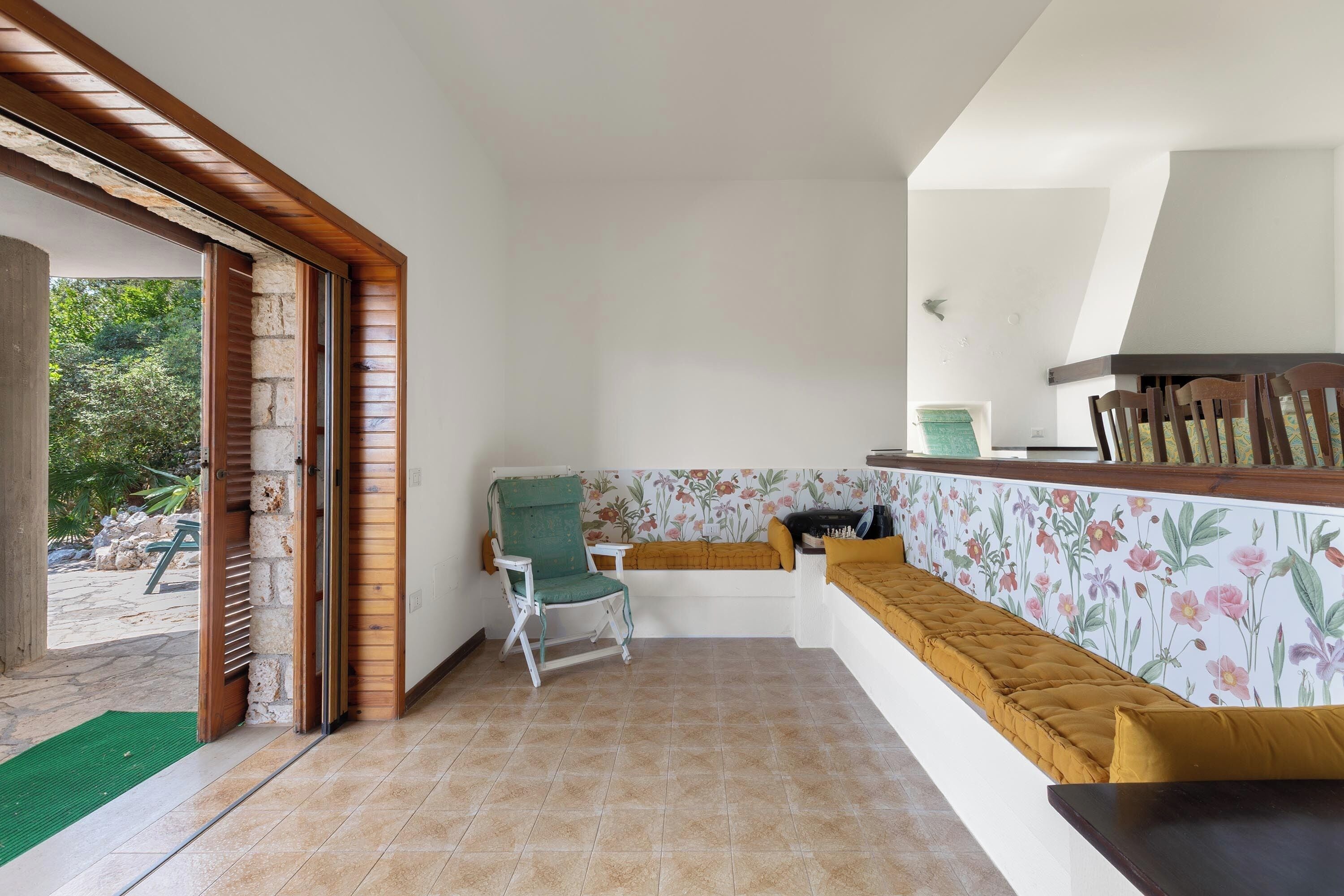 Una habitación con un banco, una silla, una pequeña mesa y vistas al exterior.