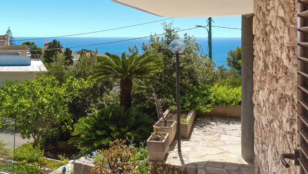 A balcony with a stone floor, potted plants, and a view of the sea. - Villa Natura by BarbarHouse (Santa Cesarea Terme)