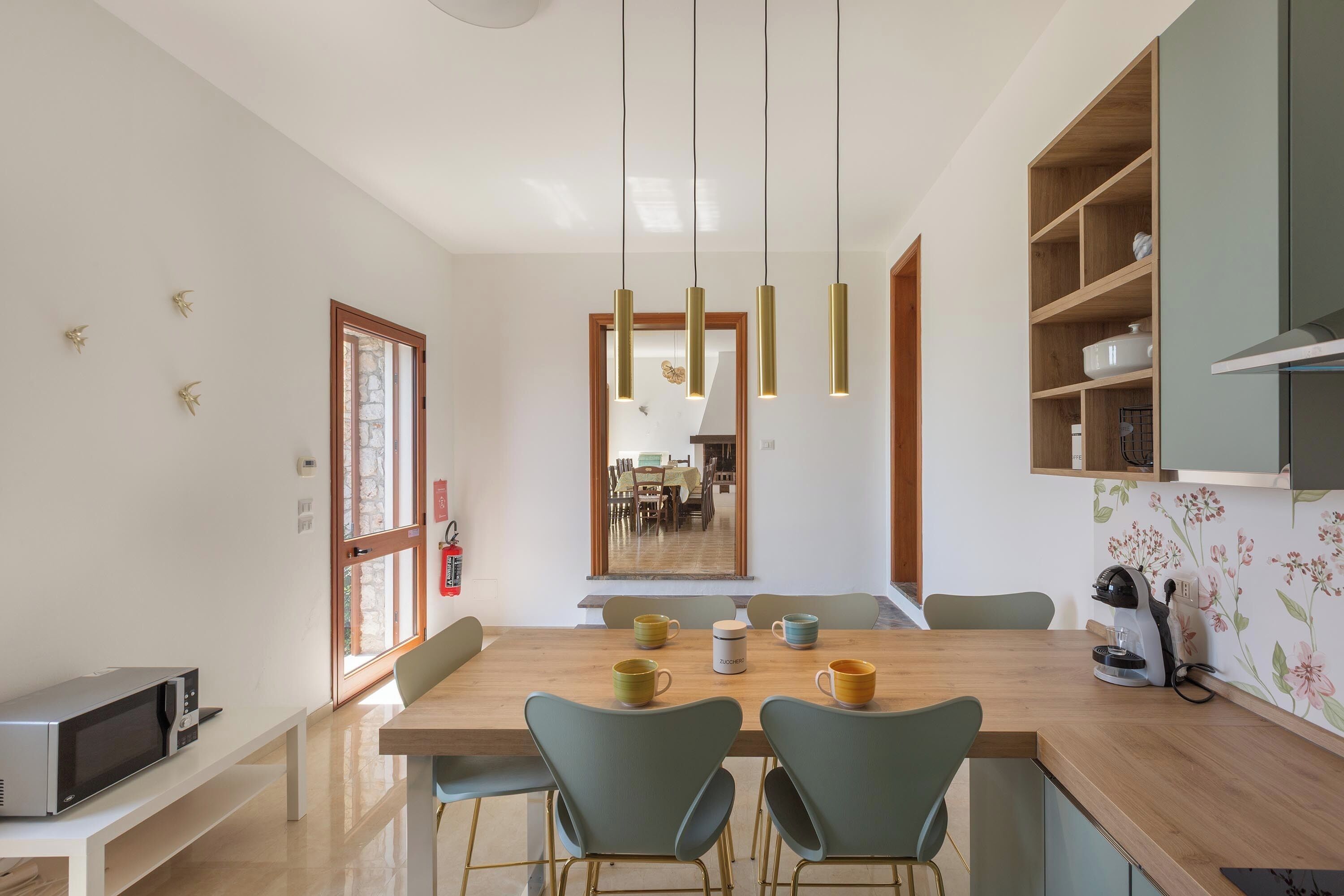 Un comedor moderno con una mesa de madera, cuatro sillas y lámparas colgantes.