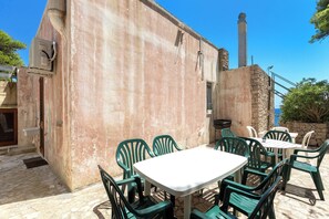 An outdoor patio with a table and chairs, a stone wall, and a chimney.