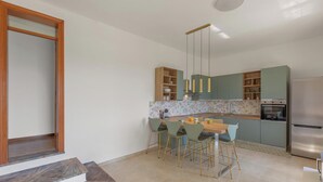 A modern kitchen with a dining area, featuring a wooden staircase, a stainless steel refrigerator, and a floral backsplash. - Villa Natura by BarbarHouse (Santa Cesarea Terme)
