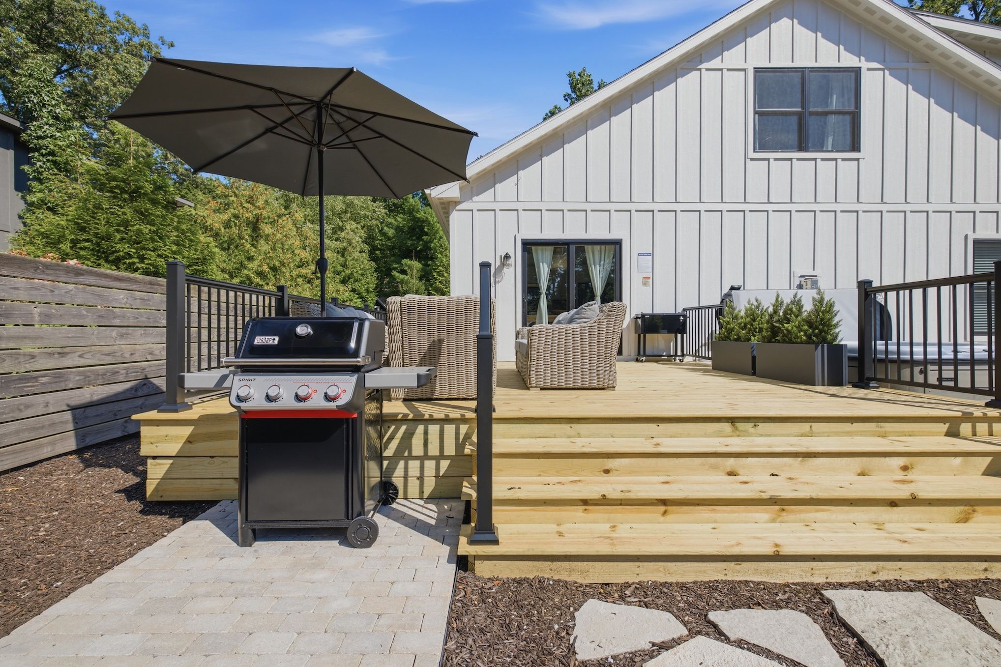 Un barbecue, des sièges d’extérieur et une terrasse en bois menant à un bâtiment.