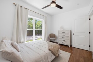 A bedroom with a bed, a dresser, a chair, and a window with curtains. - It's A Wonderful Life - Union Pier, MI (New Buffalo)