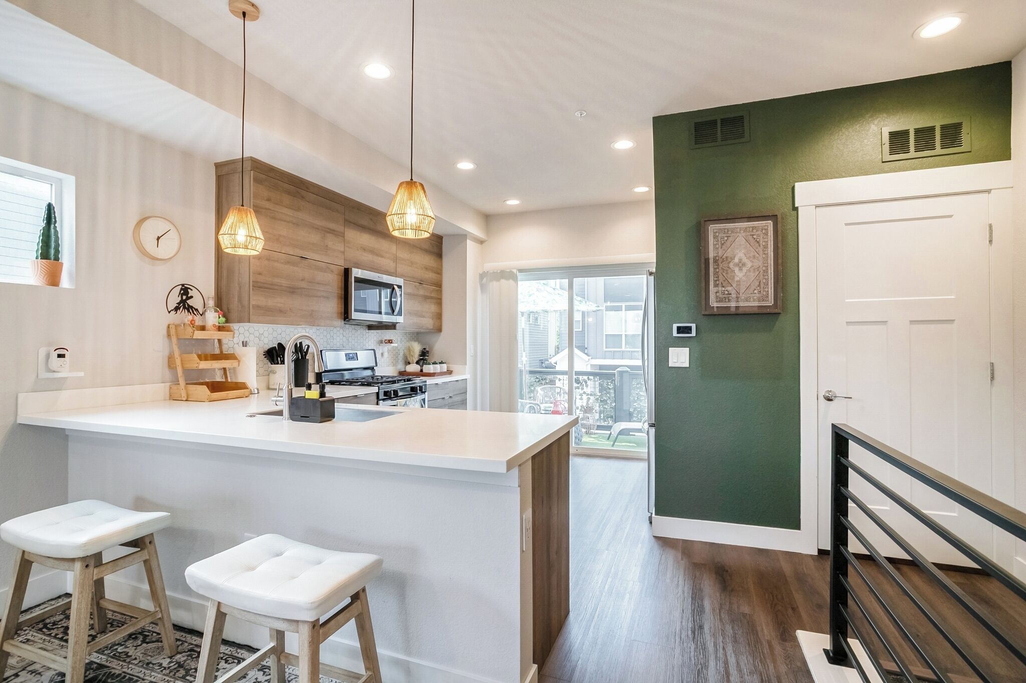 A modern kitchen with a central island, wooden cabinets, and pendant lighting.