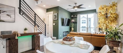 A modern living room with a staircase, a dining area with a round table, and a sofa.