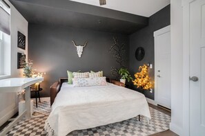 Ein Schlafzimmer mit Bett, Nachttisch, Stuhl und einer Wanddekoration.