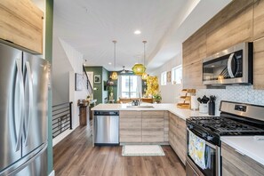 A modern kitchen with stainless steel appliances, wooden cabinetry, and a central island. - Stylish Denver Retreat Townhome (Denver)