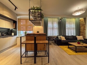 A modern kitchen with a dining area, a black sofa, and a yellow rug. - Fully equipped serviced apartment for modern & independent explorers. (Katowice)