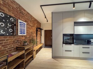 A modern kitchen with white cabinets and a black countertop. - Fully equipped serviced apartment for modern & independent explorers. (Katowice)