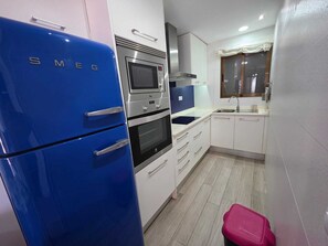 Eine Küche mit einem blauen Kühlschrank, einer Mikrowelle, einem Backofen und einem Spülbecken.