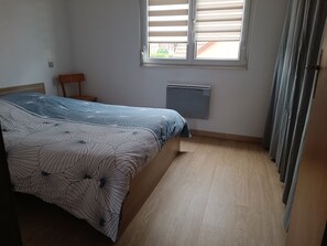 A bedroom with a bed, a radiator, a window with blinds, and a curtain. - Vrbo Property (Geispolsheim)