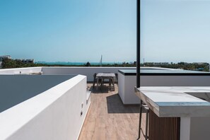 Eine Dachterrasse mit Tisch und Stühlen mit Blick auf eine Küstenstadt.