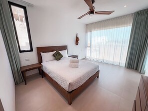A bedroom with a bed, a nightstand, a ceiling fan, and a window with curtains. - Casa Nueva con Alberca y Rooftop con Vista al Mar! (Isla Mujeres)