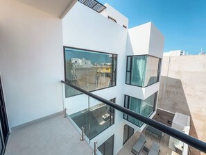 Um edifício moderno de vários andares com varandas, amplas janelas e vista desobstruída da região.