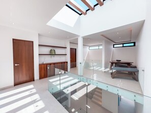 A modern interior with a glass staircase, wooden door, and a seating area with a table. - Casa Nueva con Alberca y Rooftop con Vista al Mar! (Isla Mujeres)