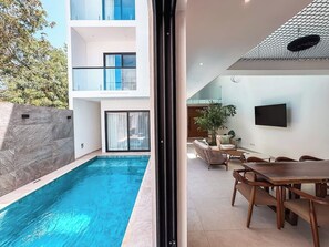 Ein modernes Gebäude mit Pool, Außenbereich und einem an der Wand befestigten Flachbildfernseher.
