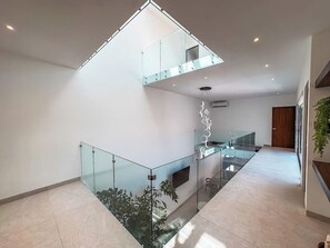 A modern interior with a glass staircase, a mezzanine level, and a minimalist design. - Casa Nueva con Alberca y Rooftop con Vista al Mar! (Isla Mujeres)