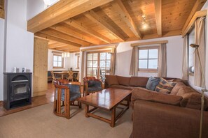 A spacious living area with a wooden ceiling, a sofa set, a dining table with chairs, and a fireplace. - Serene Wald im Pinzgau Chalet With Pool (Wald im Pinzgau)