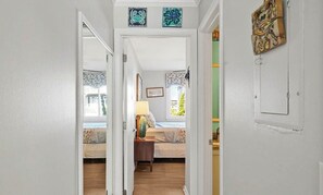 Un couloir menant à une chambre à coucher équipée d’un lit, d’une table de chevet et d’une fenêtre.