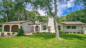 A two-story house with a covered patio, a white exterior, and a well-maintained lawn. - Gem at Crystal River (Crystal River)