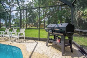 A poolside area with a grill and lounge chairs. - Gem at Crystal River (Crystal River)